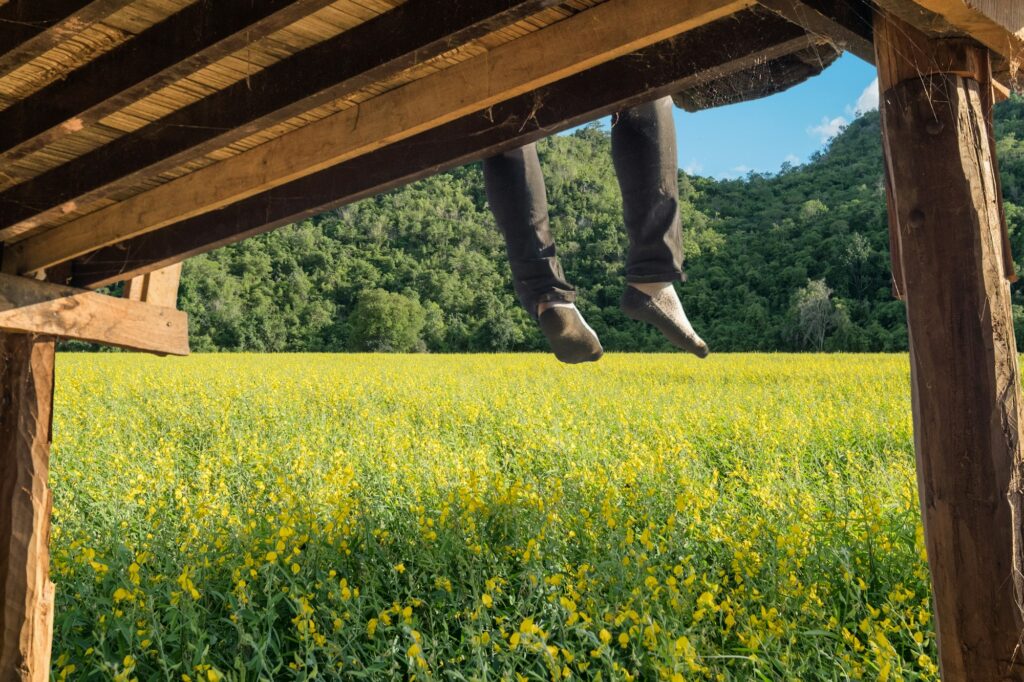 Tourist relaxing and hanging leg on wood terrace in plantation